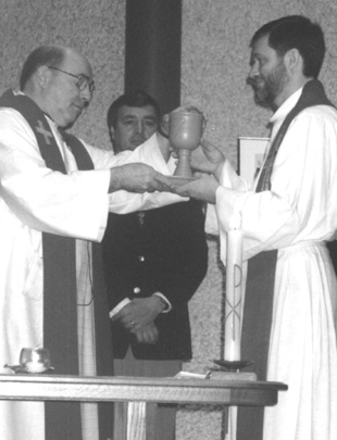 EXCHANGE OF GIFTS -- Gifts of identical chalices and patens are exchanged by Rev. Bernard de Margerie, left, of Holy Spirit Roman Catholic Church, and Rev. Ron McConnell of McClure United. The exchange is symbolic of the yearning and hunger for full eucharistic communion and the commitment to the work and ministry of reconciliation and healing