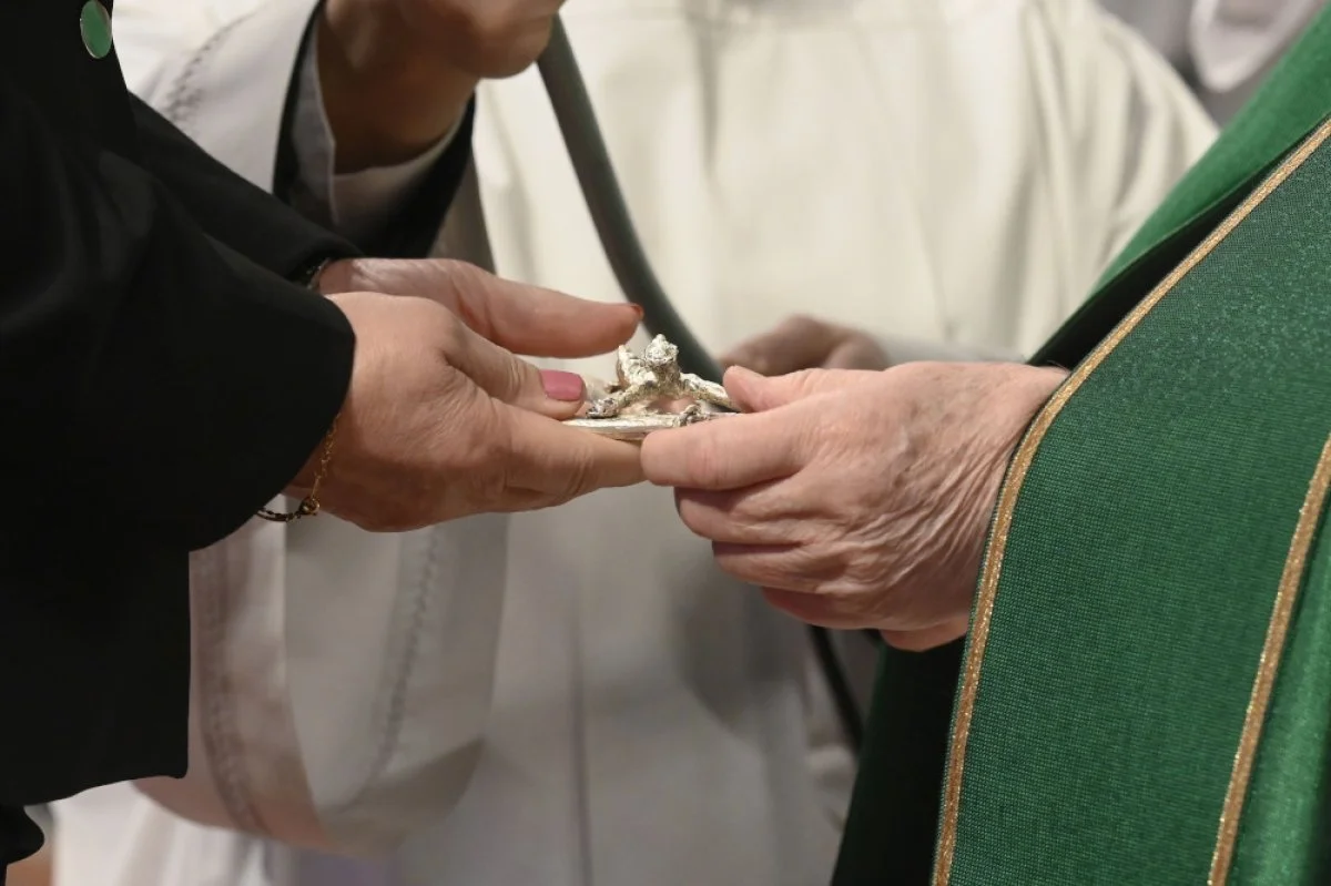 Pope Francis gives a crucifix to a layperson he installed as a catechist during a Mass in St. Peter's Basilica at the Vatican. The Dicastery for Laity, the Family and Life is sponsoring a conference aimed at promoting the