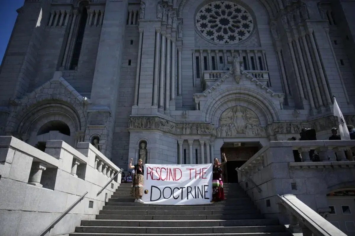 Sarain Fox, right, and Chelsea Brunelle of the Batchewana First Nation demonstrate outside the Mass presided over by Pope Francis in Sainte-Anne-de-Beaupré, Québec