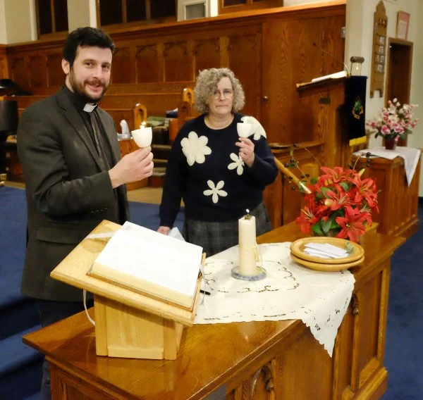 Rev. Roberto DeSandoli of St. Andrew Presbyterian Church and Cathryn Wood of the Prairie Centre for Ecumenism light candles from a common flame, before sharing with those attending the service