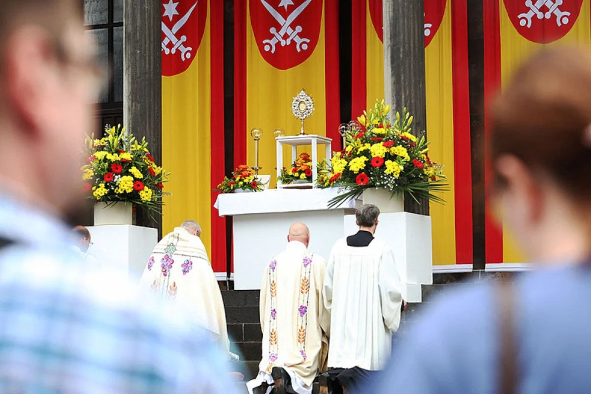 The Corpus Christi procession pauses for prayer at the flag-draped St. Gertrud Church in Essen, Germany. During the procession Bishop Franz-Josef Overbeck of Essen offered support for allowing a Protestant married to a Catholic to receive Communion as a sign of Christian unity