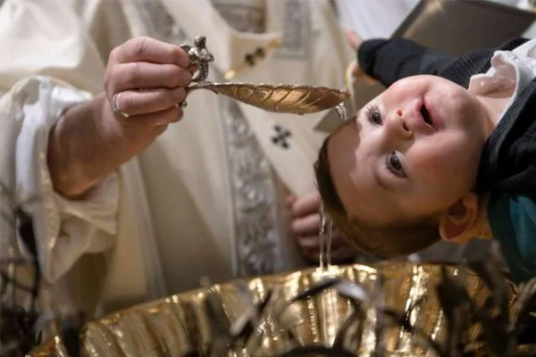 Pope Francis baptizes a baby as he celebrates Mass on the feast of the Baptism of the Lord in the Sistine Chapel at the Vatican