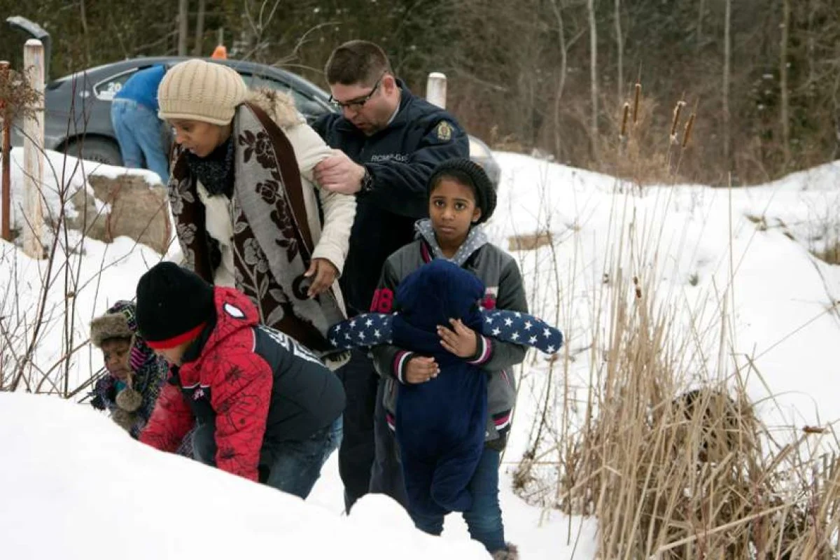 A woman who told police that she and her family were from Sudan is taken into custody by a Royal Canadian Mounted Police officer after arriving Feb.12 by taxi and walking across the U.S.-Canada border into Quebec