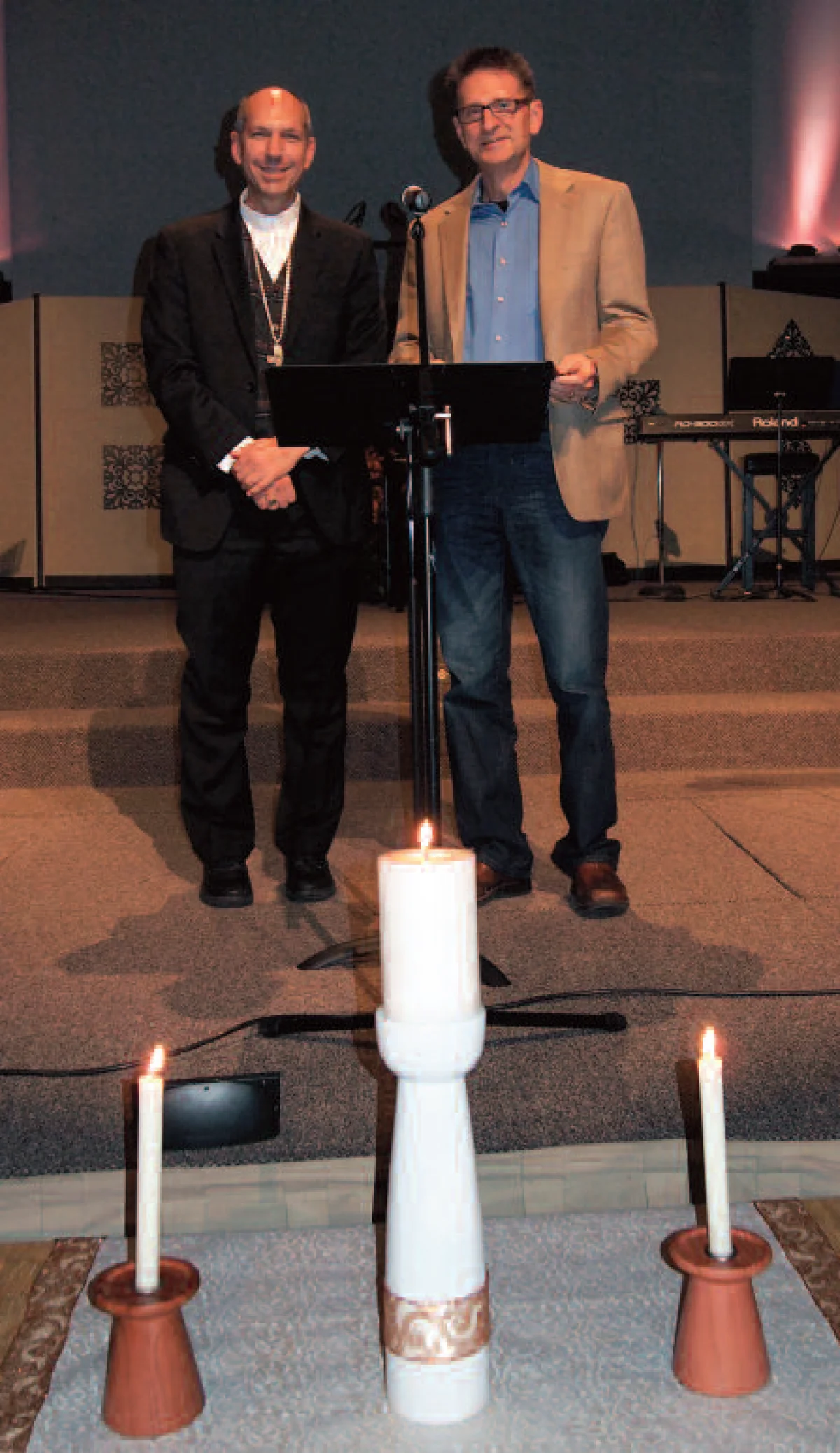 Bishop Don Bolen (left) and Rev. Eldon Boldt standing before the candles each carried in procession at the second Catholic-Evangelical worship service