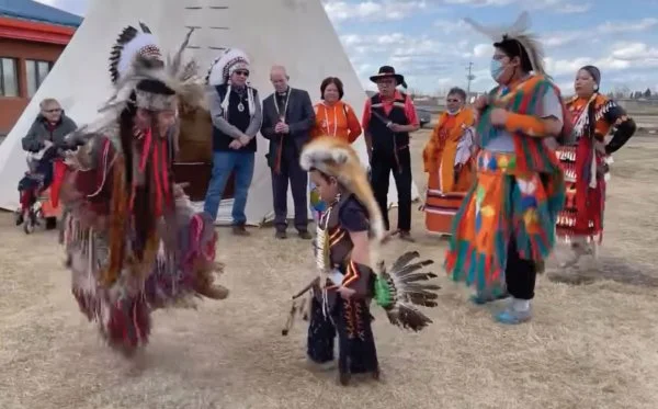 Archbishop Justin Welby, with local leaders at James Hill Cree Nation, watches a traditional dance. Left to right: Reverend Martha Stonestand, James Smith Cree Nation, retired; Michael Charles, dancer; Emmerick Stonestand, dancer; Chief Rob Head, Peter Chapman Cree Nation; Justin Welby, Archbishop of Canterbury; Florence Sanderson, Head-Woman Chakastaypasin First Nation; Sandra Sanderson; McKenzie Stonestand, dancer; Taylor Brittain, dancer