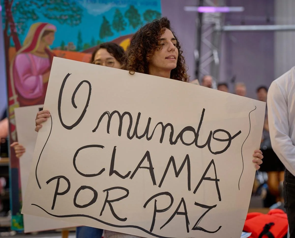 Young people hold signs during the morning prayer service at the World Council of Churches' 11th Assembly in Karlsruhe, Germany. The Assembly's theme is 'Christ's Love Moves the World to Reconciliation and Unity'