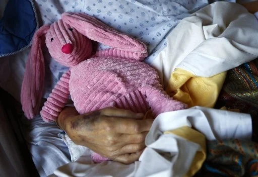 A dying cancer patient holds a stuffed animal during her final hours at a palliative care hospital in Winnipeg, Manitoba