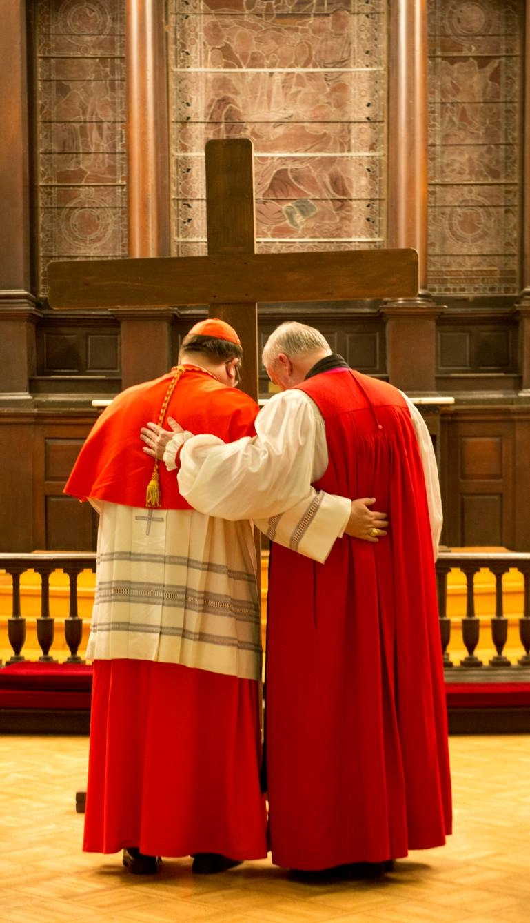 Cardinal Gérald Cyprien Lacroix (left), Roman Catholic archbishop of Quebec and Bishop Dennis Drainville (right) of the Anglican Diocese of Quebec embrace before the cross