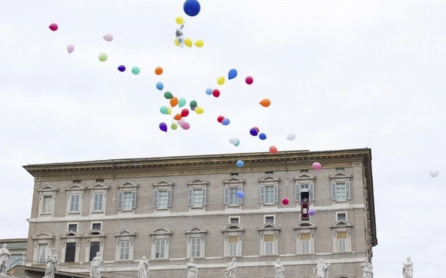 Balloons are released as Pope Francis recites the Angelus noon prayer from his studio overlooking St Peter's Square at the Vatican