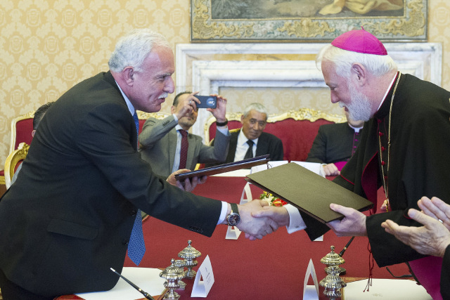 Archbishop Paul Richard Gallagher, right, Vatican secretary for relations with states, and Palestinian Foreign Minister Riyad al-Malki shake hands during a meeting at the Vatican June 26. The Vatican signed its first treaty with the 'State of Palestine' calling for 'courageous decisions' to end the Israeli-Palestinian conflict with a two-state solution. Photo: CNS/L’Osservatore Romano via Reuters