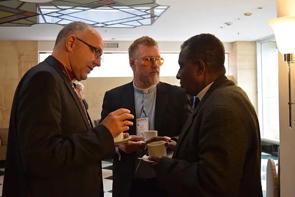 Discussion at the International Lutheran Council’s 2015 World Conference spills into the coffee break. Bishop Hans Jorg Voigt (ILC Chairman and head of the Independent Evangelical Lutheran Church in Germany) and Chairman Jon Ehlers (Evangelical Church of England) speak with General Secretary Ofga Berhanu (Ethiopian Evangelical Church Mekane Yesus)