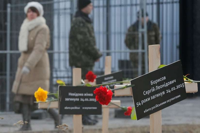 Ukrainians walk past symbolic crosses set up by protesters in front of the Russian embassy in Kiev, Ukraine