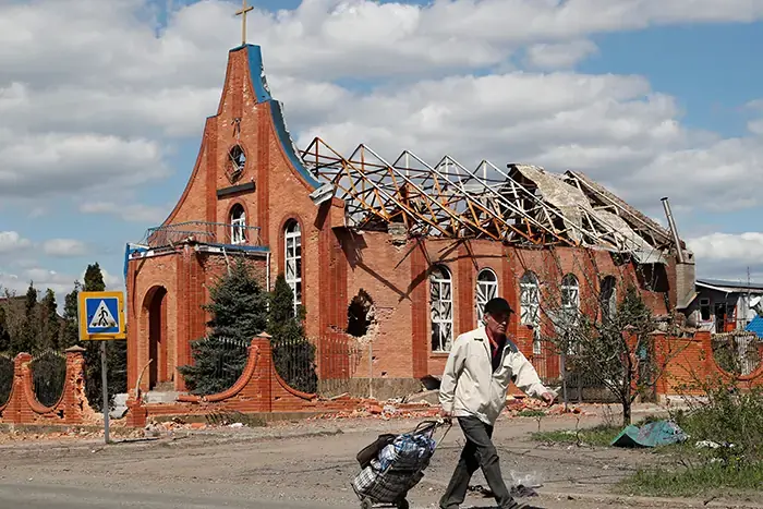 A local resident walks past a church heavily damaged during Ukraine-Russia conflict in the southern port city of Mariupol, Ukraine