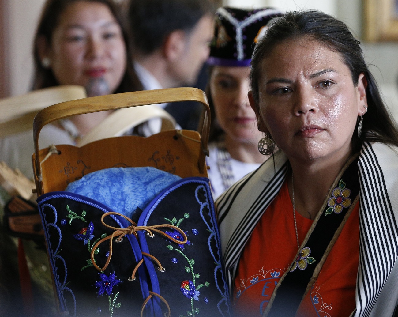 An Indigenous woman displays a cradleboard as Pope Francis meets with a delegation of Indigenous peoples in the archbishop's residence in Quebec City. Indigenous leaders want Pope Francis to help them get information about the more than 4,000 children who died at Canada's residential schools and the thousands of others who never returned home from the schools