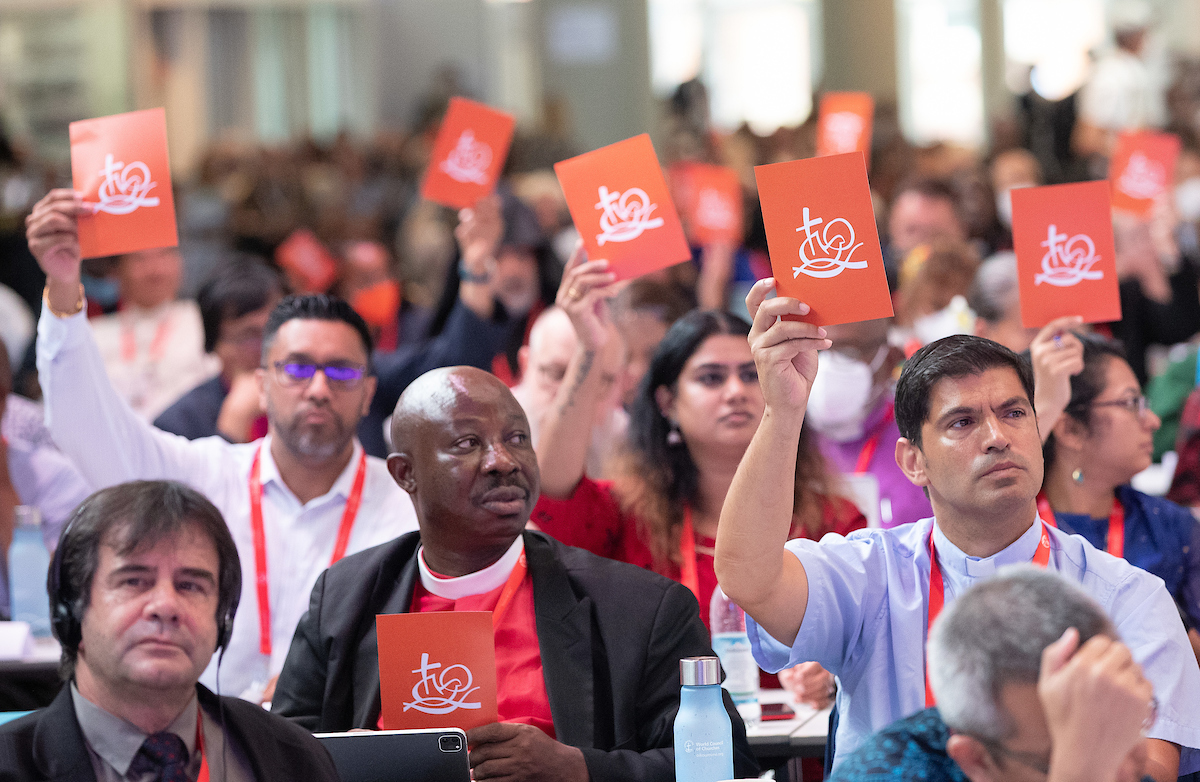 Delegates at the WCC Assembly in Karlsruhe signal their support of the draft agenda. The WCC functions using principles of consensus decision-making. Orange cards indicate consent, blue signals disagreement or that the proposal requires further work or discussion. The moderator invites delegates displaying a blue card to explain their concerns