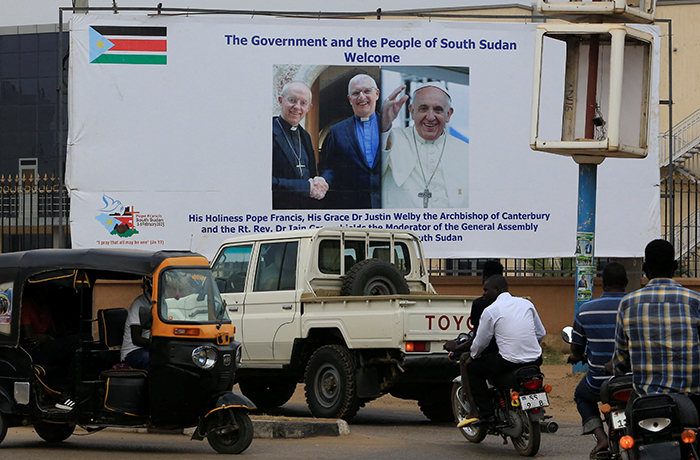 Motorists drive past a billboard showing the preparations to welcome Pope Francis, Archbishop of Canterbury Justin Welby and Church of Scotland Moderator Iain Greenshields, ahead of their visit in Juba from 3-5 February