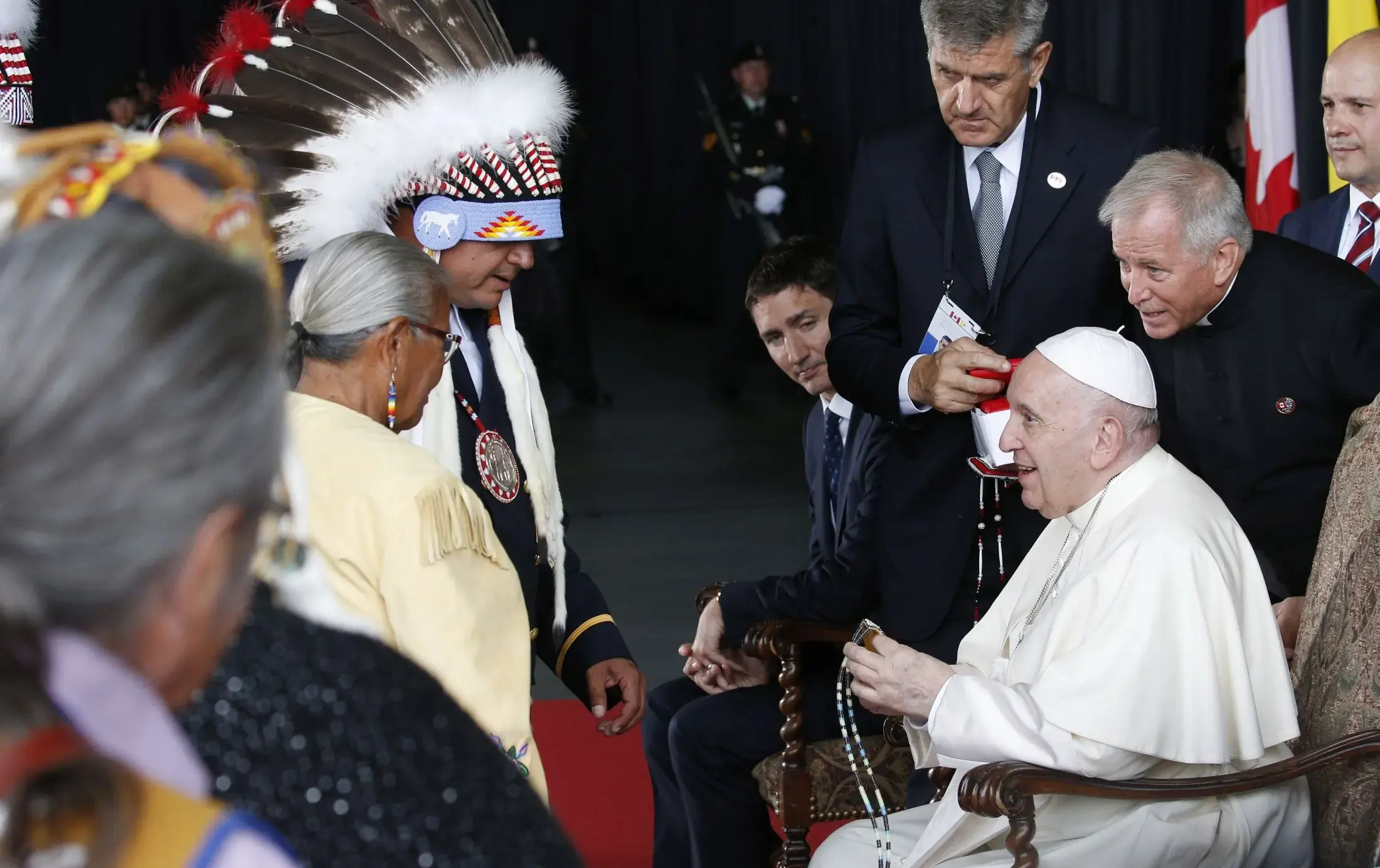Pope Francis is welcomed by Indigenous leaders, Justin Trudeau, Canada's prime minister, looking on at center, and Mary Simon, governor general, (not pictured) during a welcoming ceremony at Edmonton International Airport. The pope was beginning a six-day visit to Canada