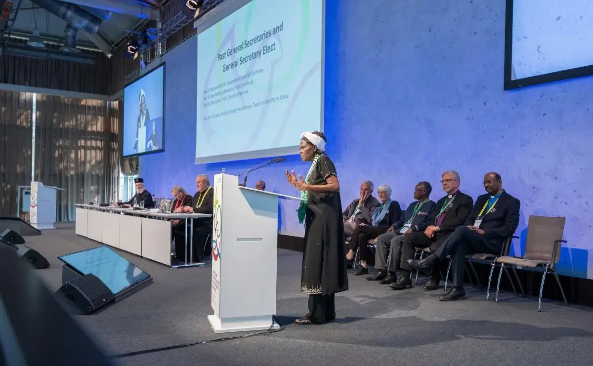 WCC central committee moderator Dr Agnes Abuom recognizes future and past WCC general secretaries at the 11th Assembly of the World Council of Churches, held in Karlsruhe, Germany from 31 August to 8 September, under the theme 'Christ’s Love Moves the World to Reconciliation and Unity.' Seated behind Abuom, from left to right: Konrad Raiser, Raiser’s wife Elisabeth, Samuel Kobia, Olav Fykse Tveit, and general secretary-elect Jerry Pillay